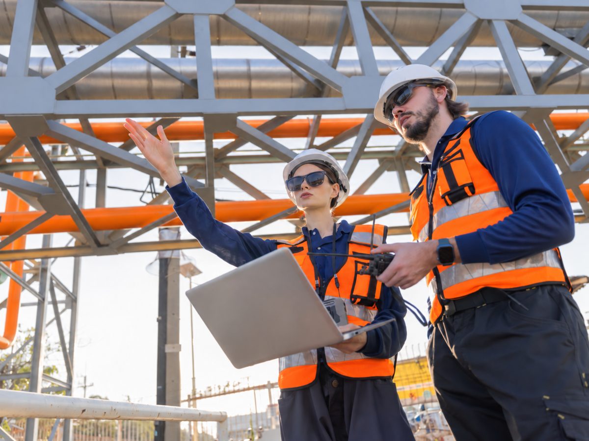 Dos personas con casco y chaleco planeando la seguridad en una instalación industrial